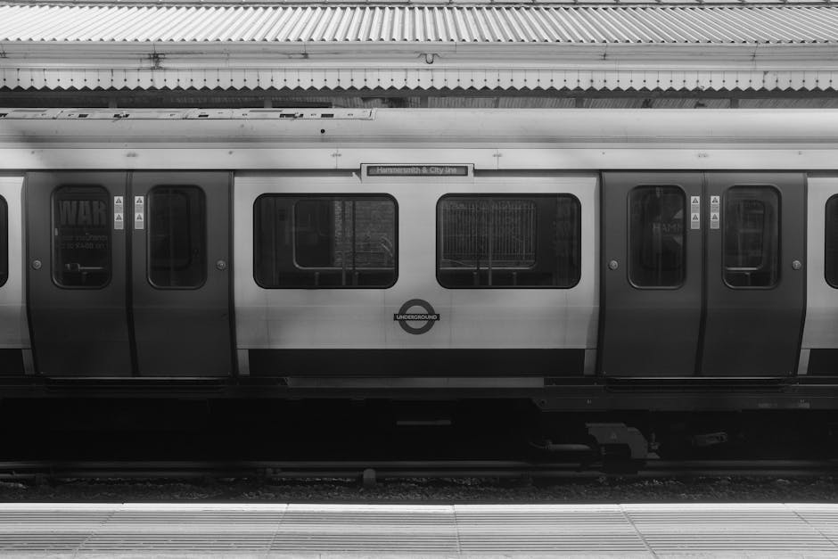 A black-and-white photograph of an underground train carriage at Hammersmith station, with the station sign visible above. The train features multiple closed doors and large windows, some with reflect